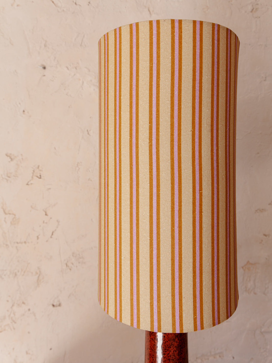 Red stoneware lamp with striped shade